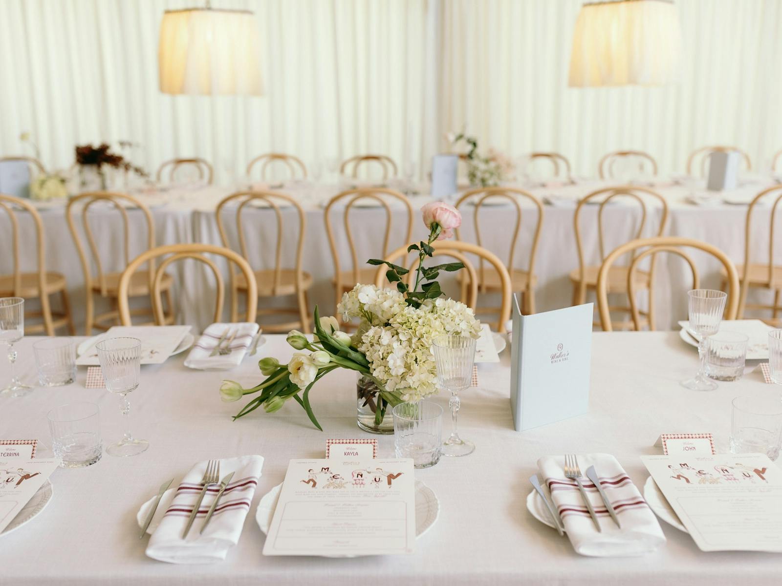 Wedding event setup with long white tables and timber beechwood chairs with floral dressings