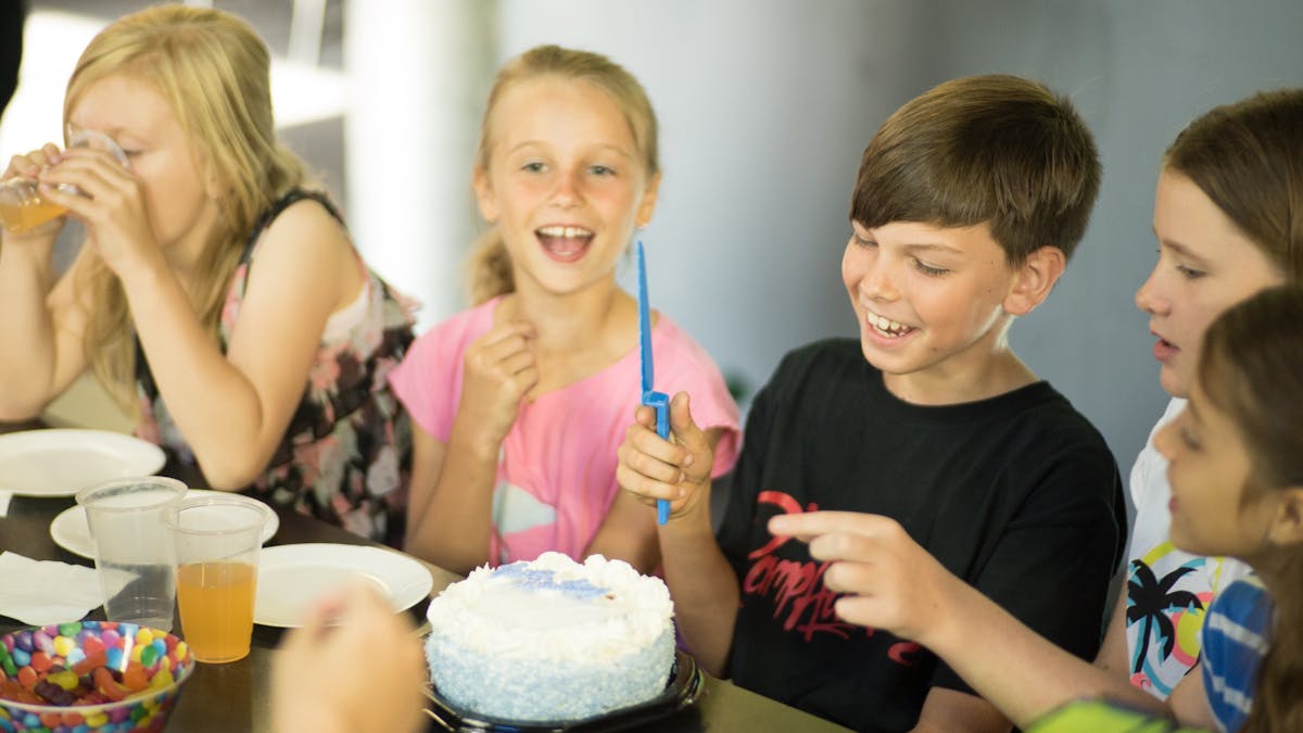 Child cutting cake at a Laserzone Sunshine Coast Birthday party surrounded by friends having fun