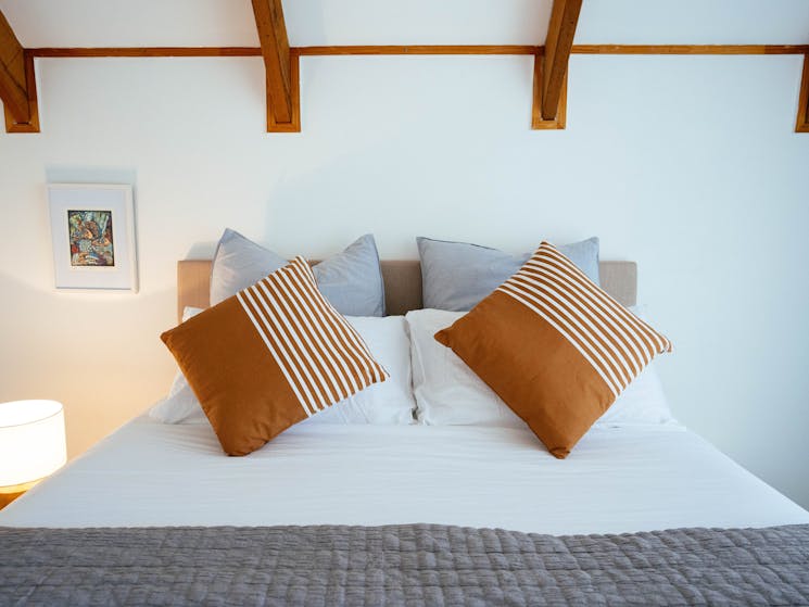 A queen sized bed with white linen and orange and light blue pillows