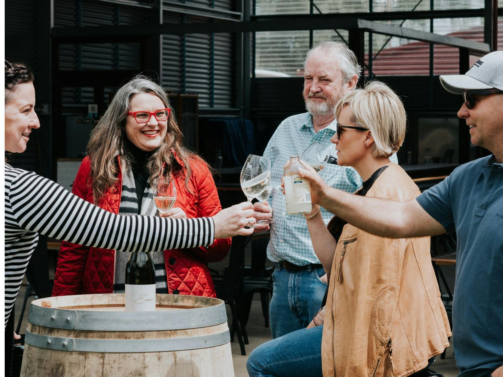 people enoying glasses of wine around a barrel