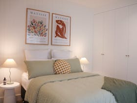 Bedroom with green bedding, bedside lamps and wall art