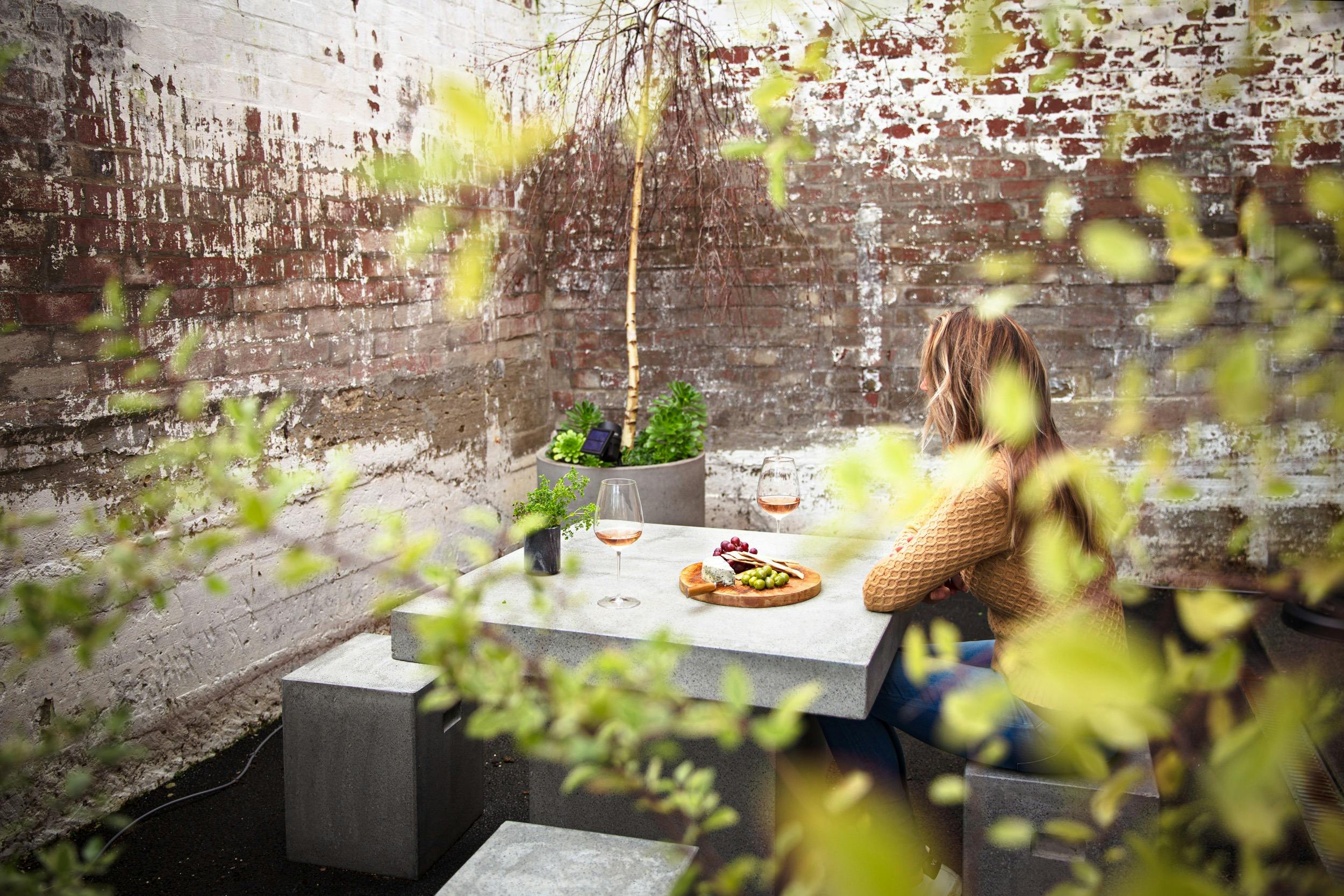 Photo shows a lady sitting at the table in the courtyard.