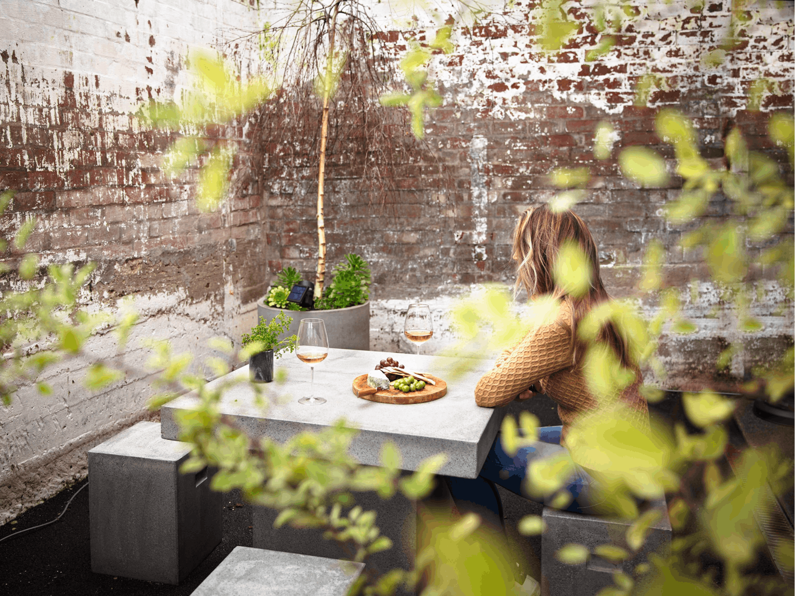 Photo shows a lady sitting at the table in the courtyard.