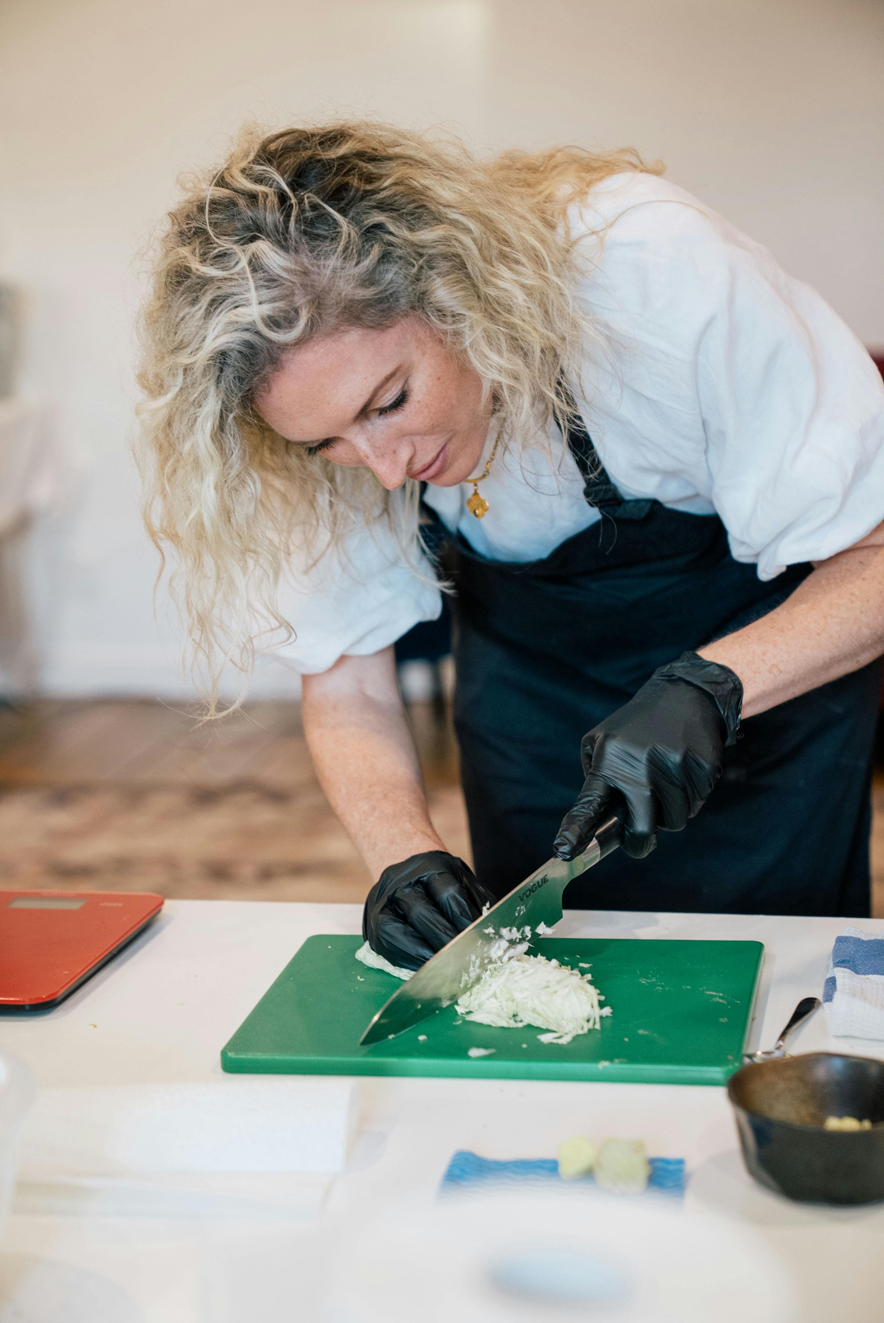 A woman in an apron cutting cabbage in the class