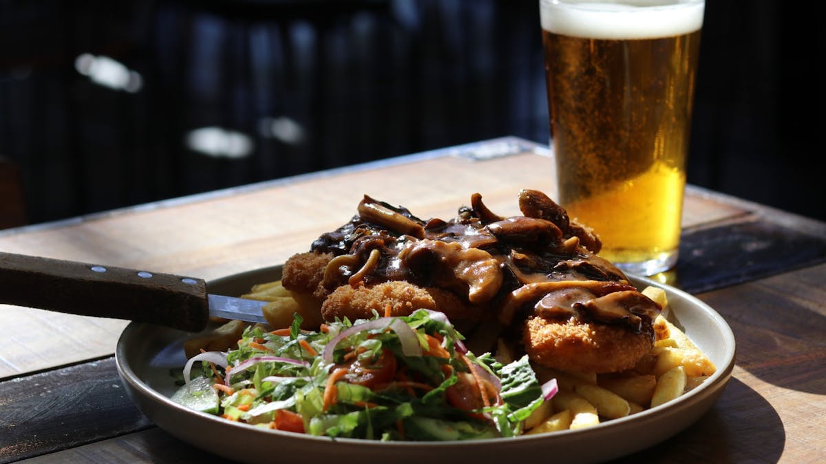 Chicken Parmy with gravy, mushrooms, salad and chips with a pint