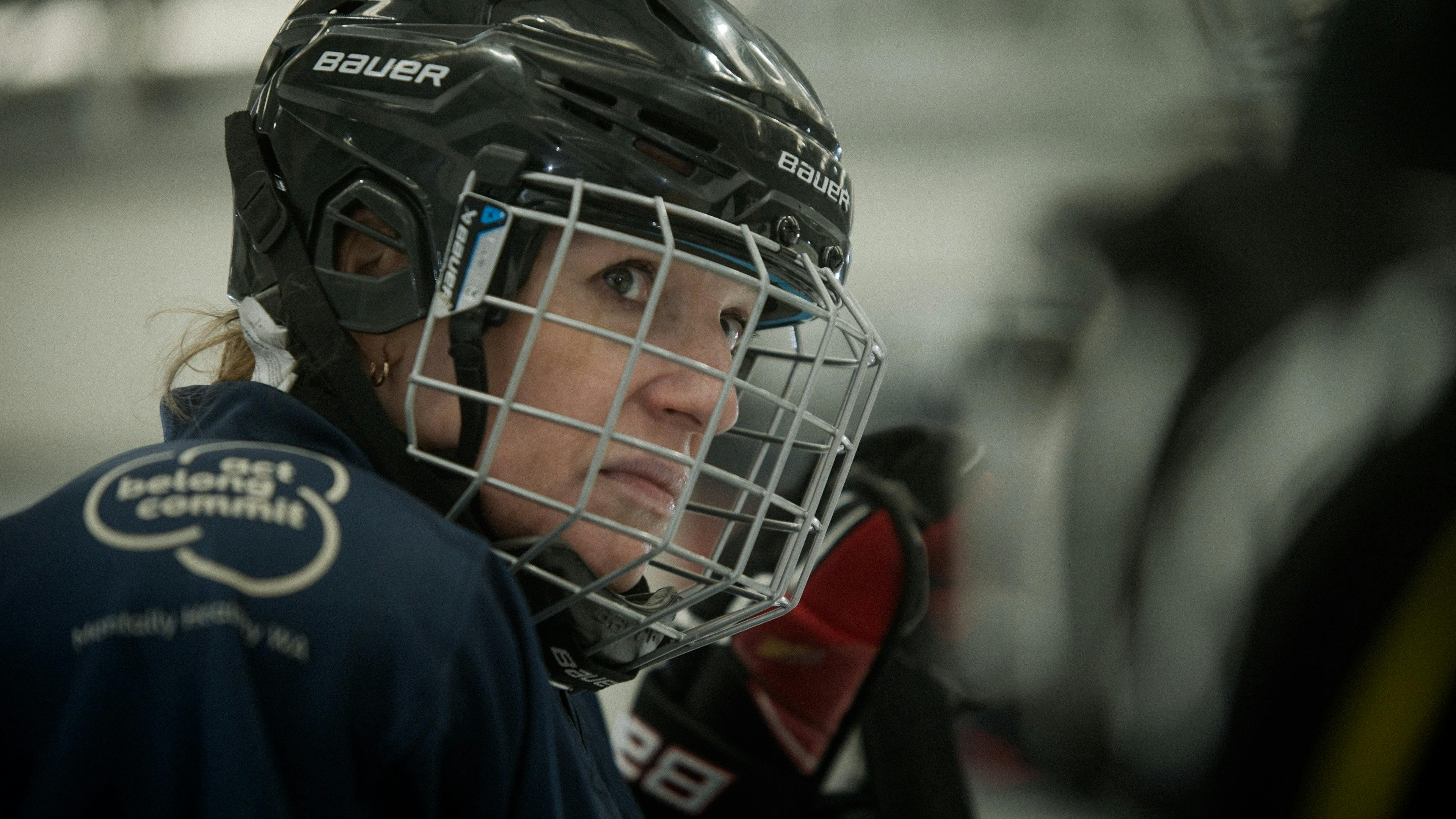 Close up of a woman in a hockey helmet looks past the camera