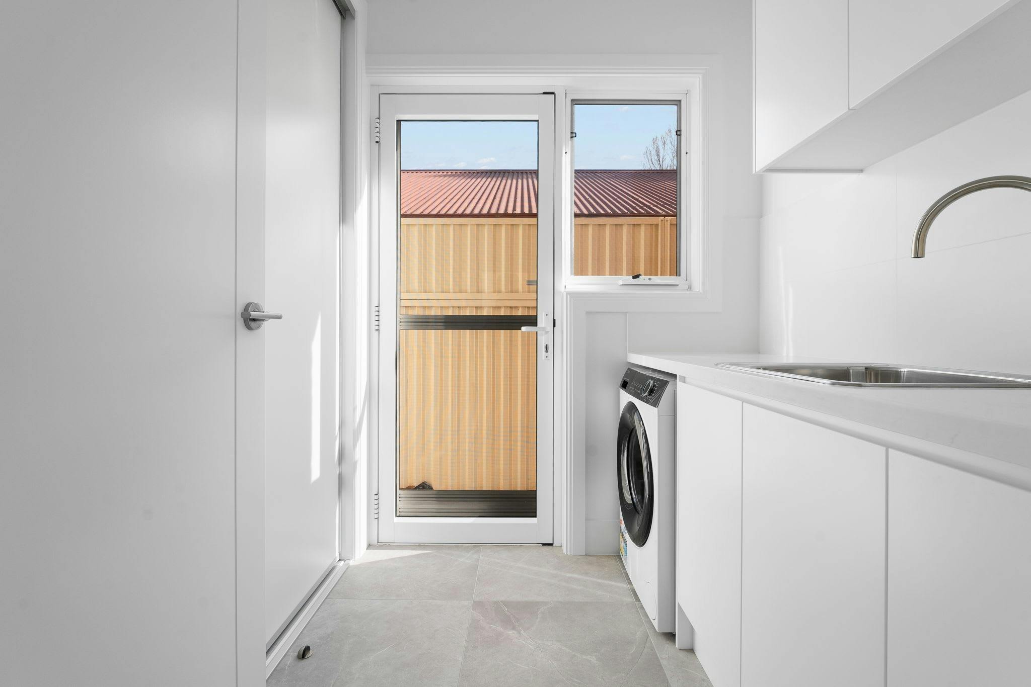 Large white laundry with storage, white cabinets and washing machine