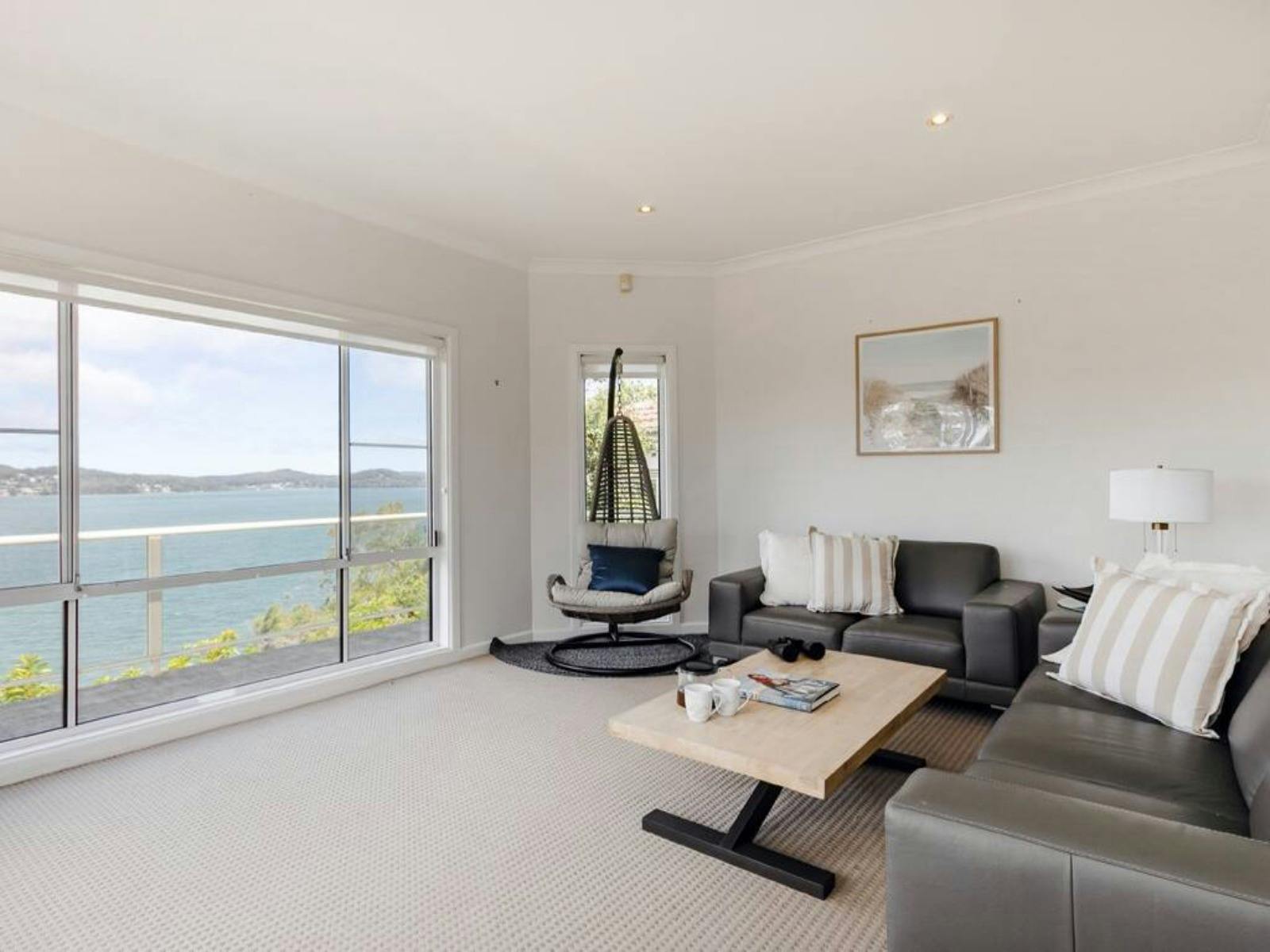 Bright living room with panoramic water views through large windows, comfortable seating and natural