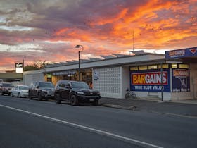 A pub in the 1960s style silhouetted by an orange sunset.