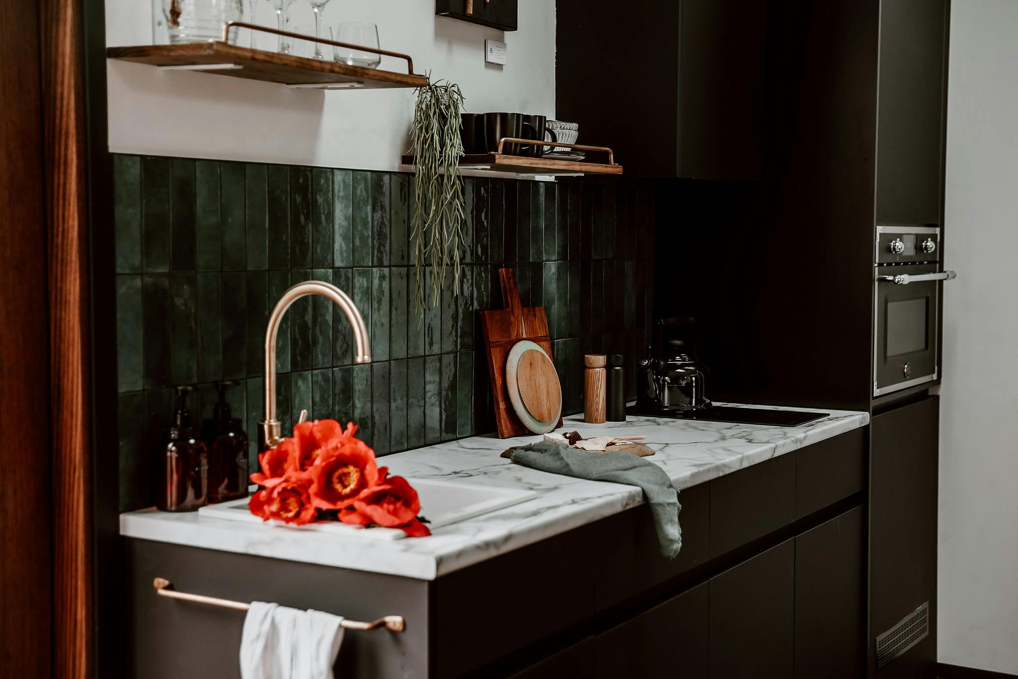 Small kitchen with green backsplash and black cabinetry.