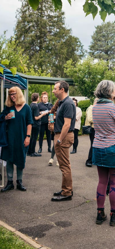 A group of poeple stand outside eating nibbles and drinking champage