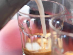Milk being poured into coffee glass