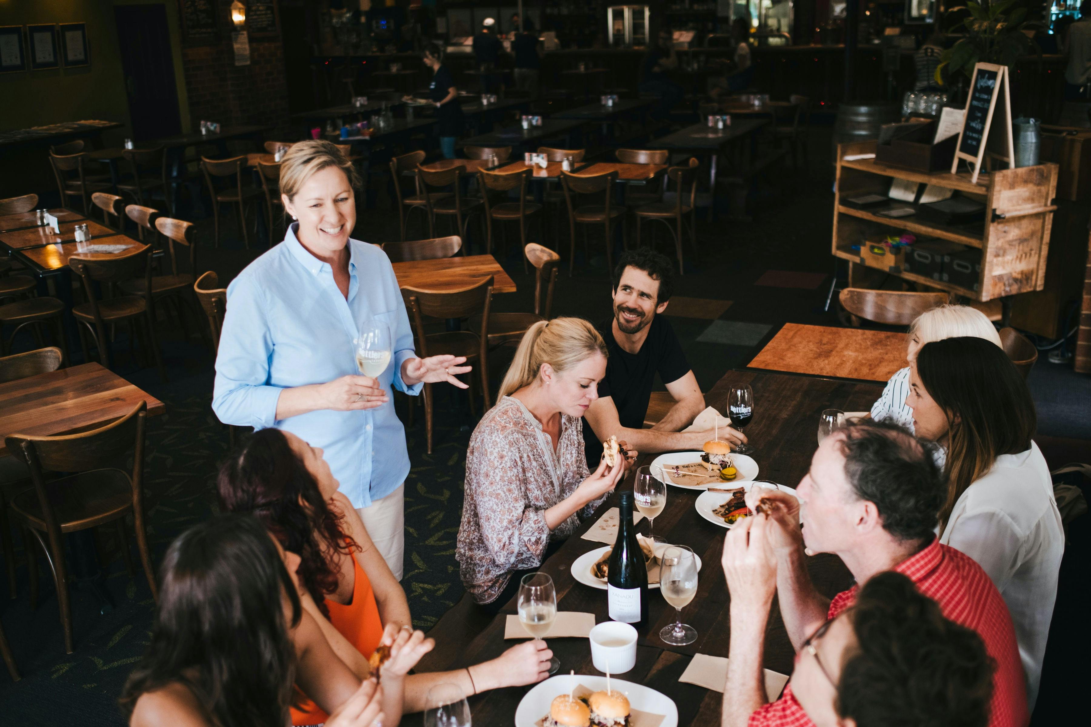 Tour host Kellie Tannock talks to guests seated at a lunch table