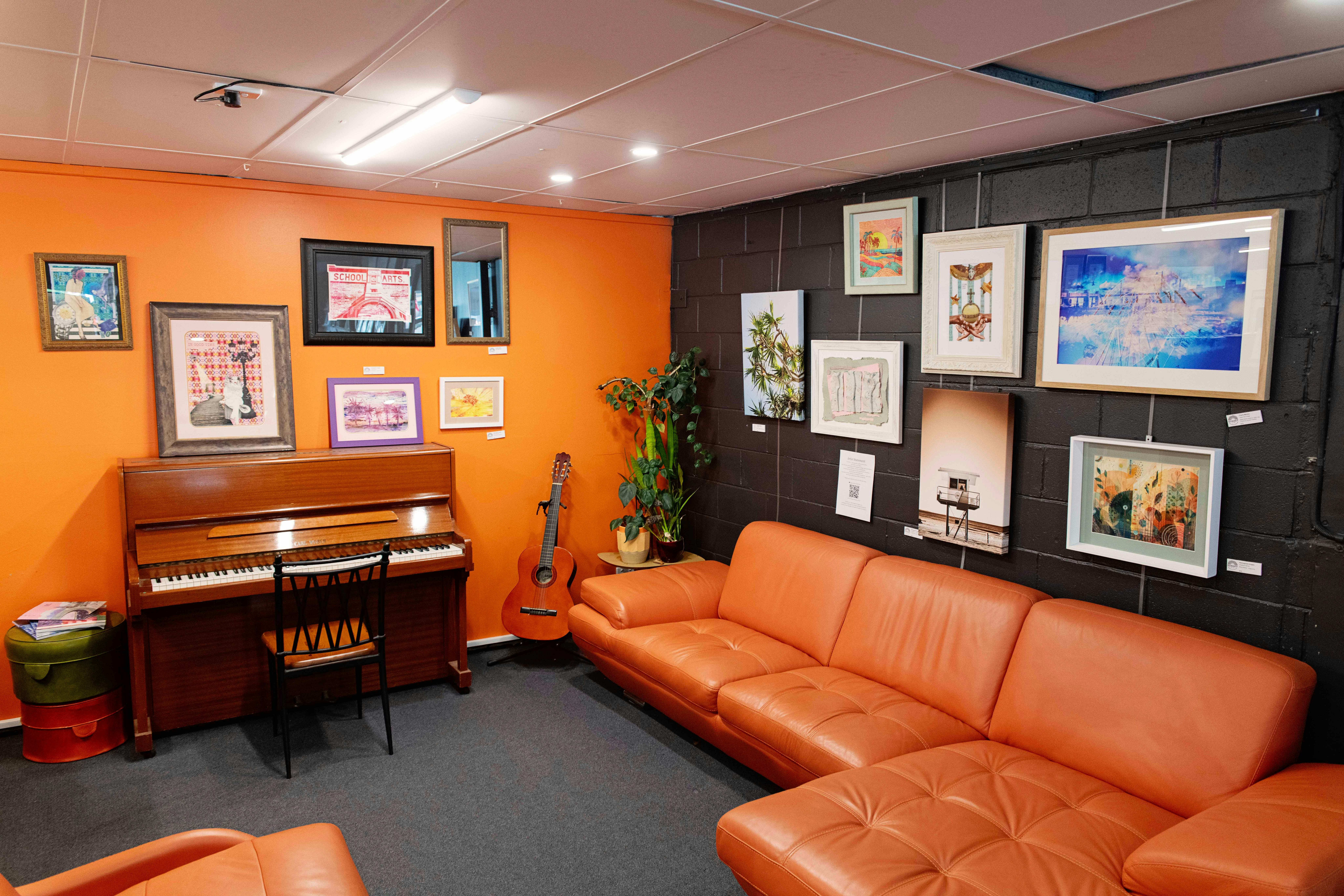 Eine Ecke einer Galerie mit Retro-Möbeln und Kunst an den Wänden.