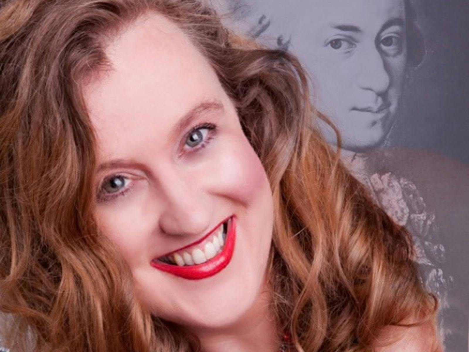 A portrait of a smiling woman with wavy brown hair and bright red lipstick.