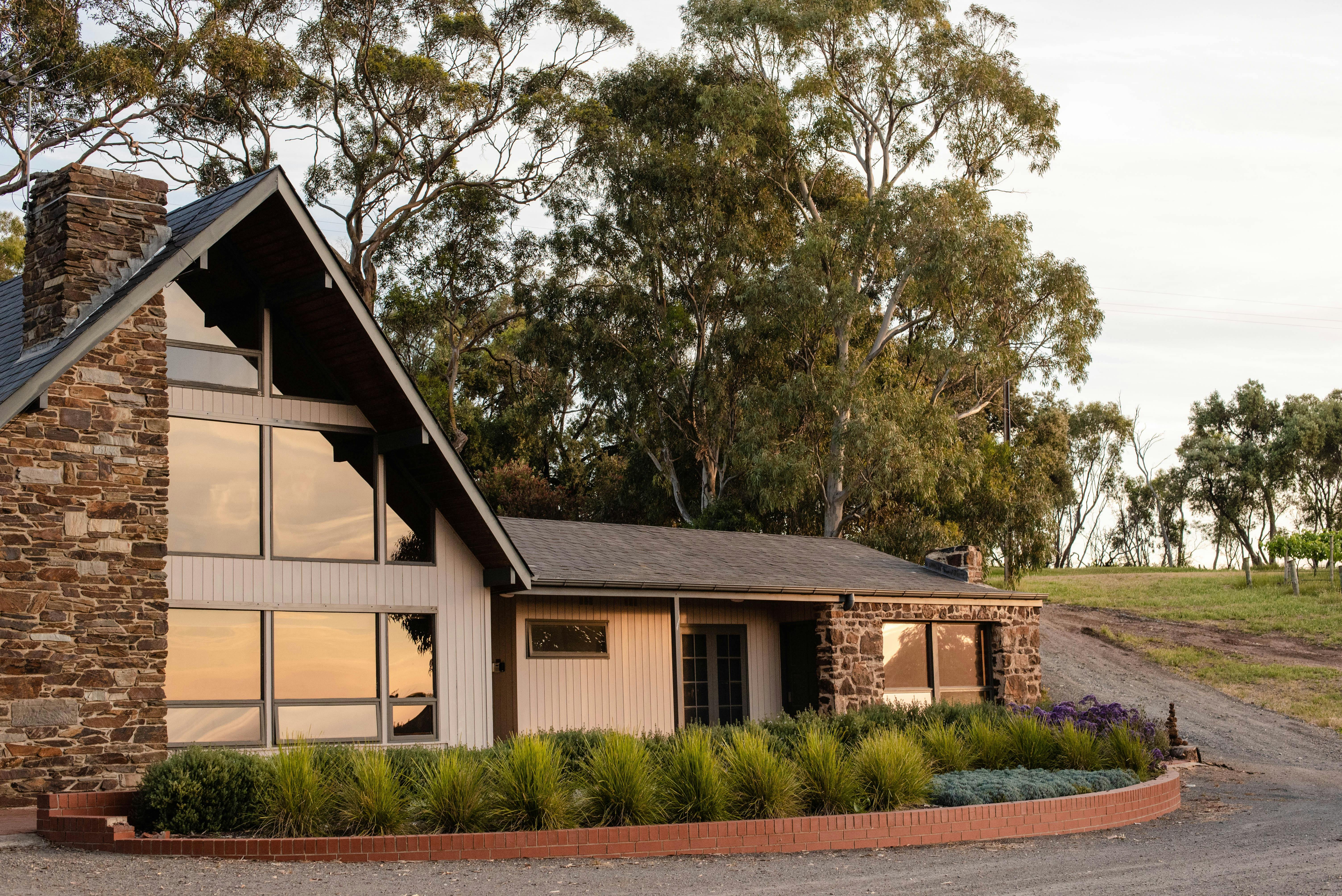 The stone Guest House at Chapel Hill, with  wall of windows looking out to the vineyard