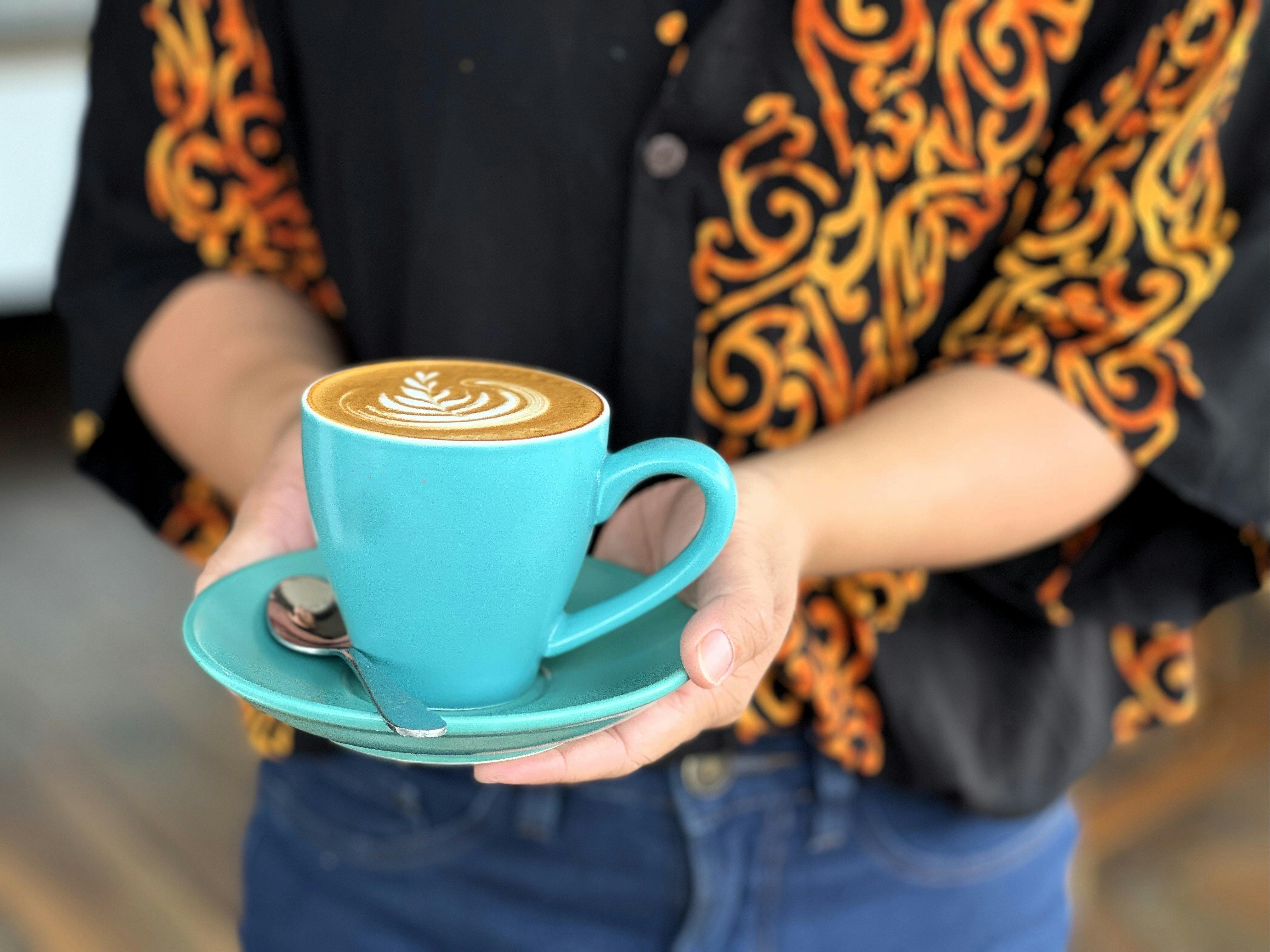 Person holding a mug of coffee at Holmes St cafe