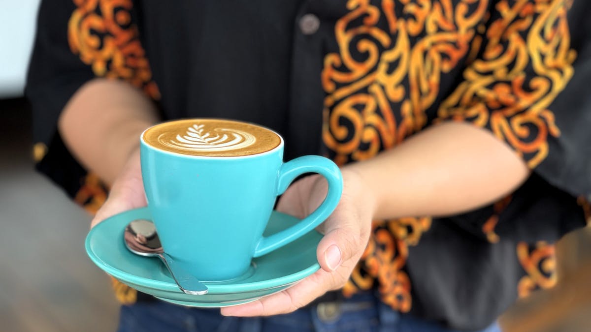 Person holding a mug of coffee at Holmes St cafe