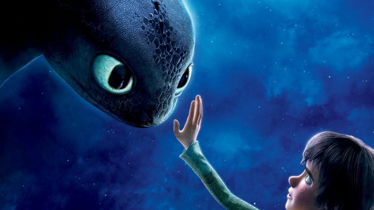 A young boy reaches out to a black dragon with gentle blue eyes, under the light of the moon.