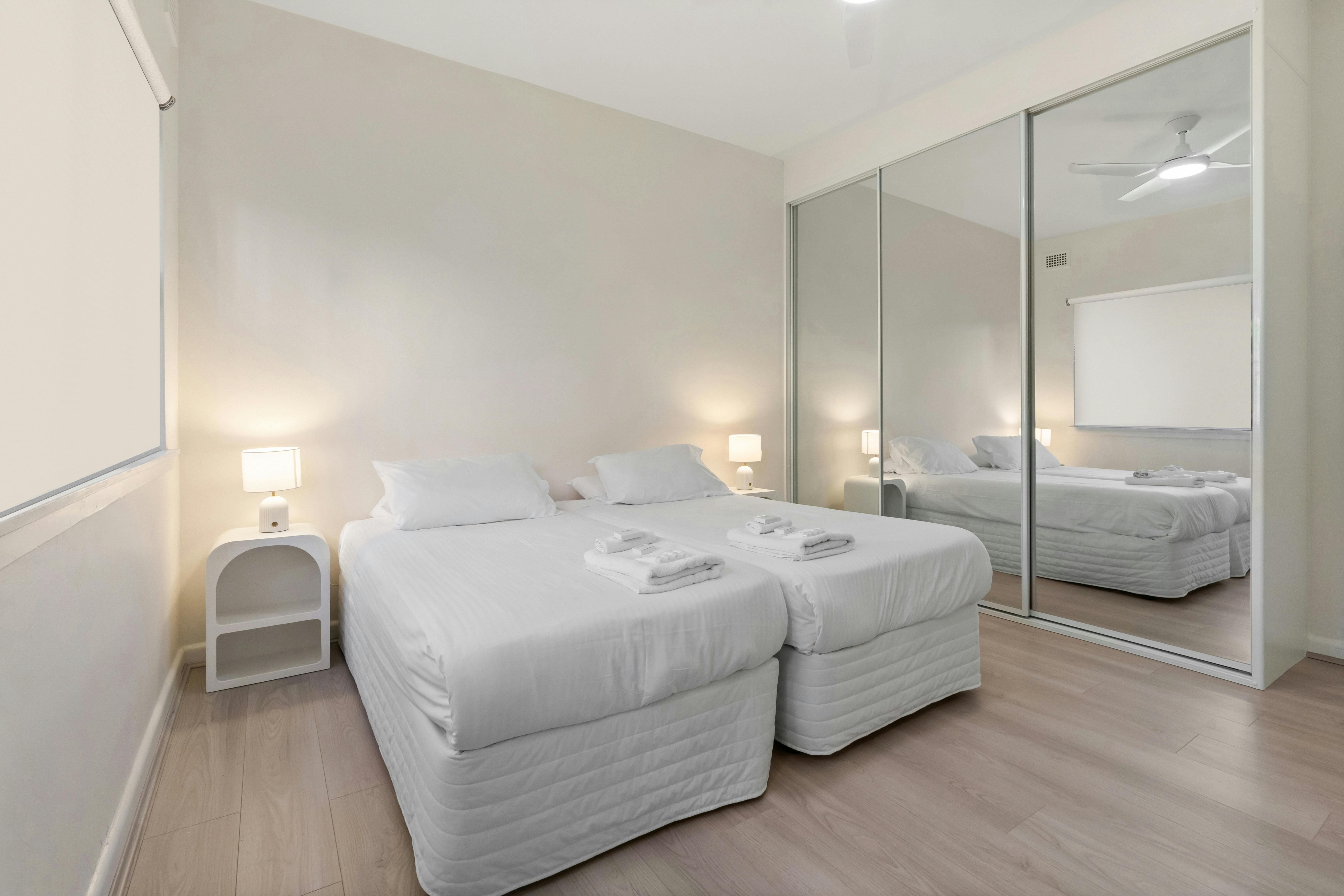 光線充足的臥室配有兩張單人床、側燈和大鏡子。