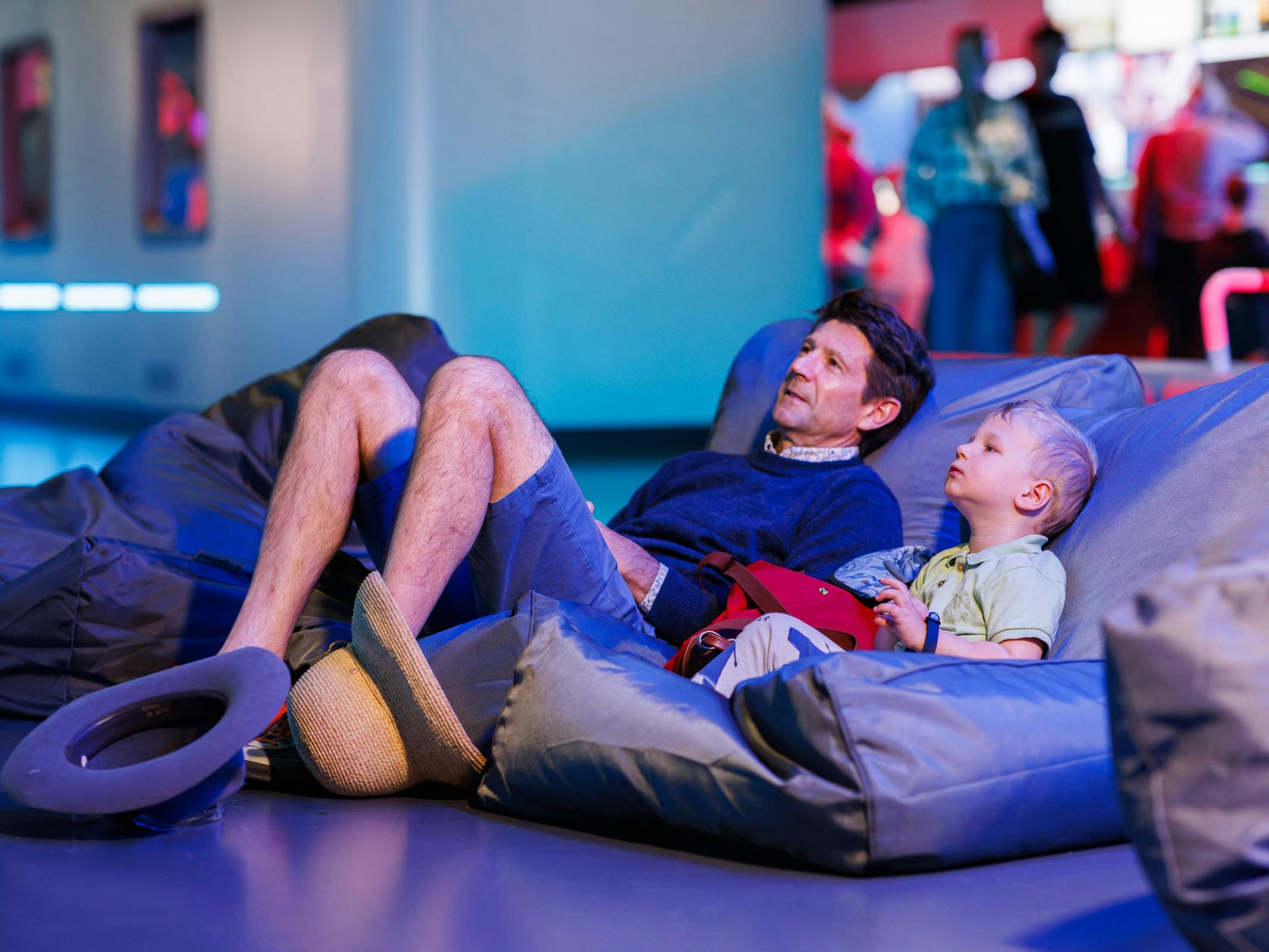 A man and his young son watch a screen from beanbags