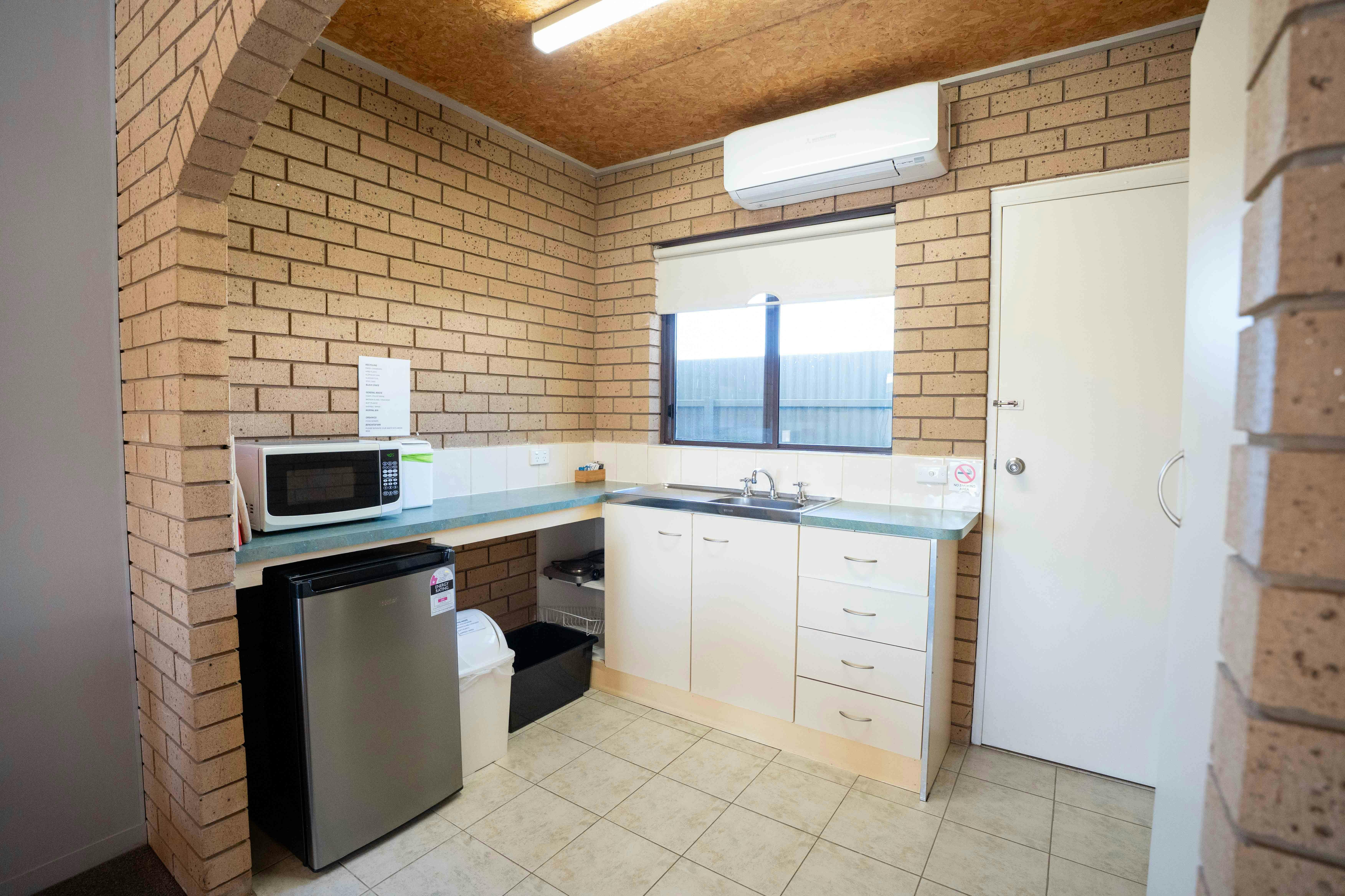 Die separate Küchenzeile ist mit Minikühlschrank, Mikrowelle, Wasserkocher, Kochfeld, Besteck und Geschirr ausgestattet.