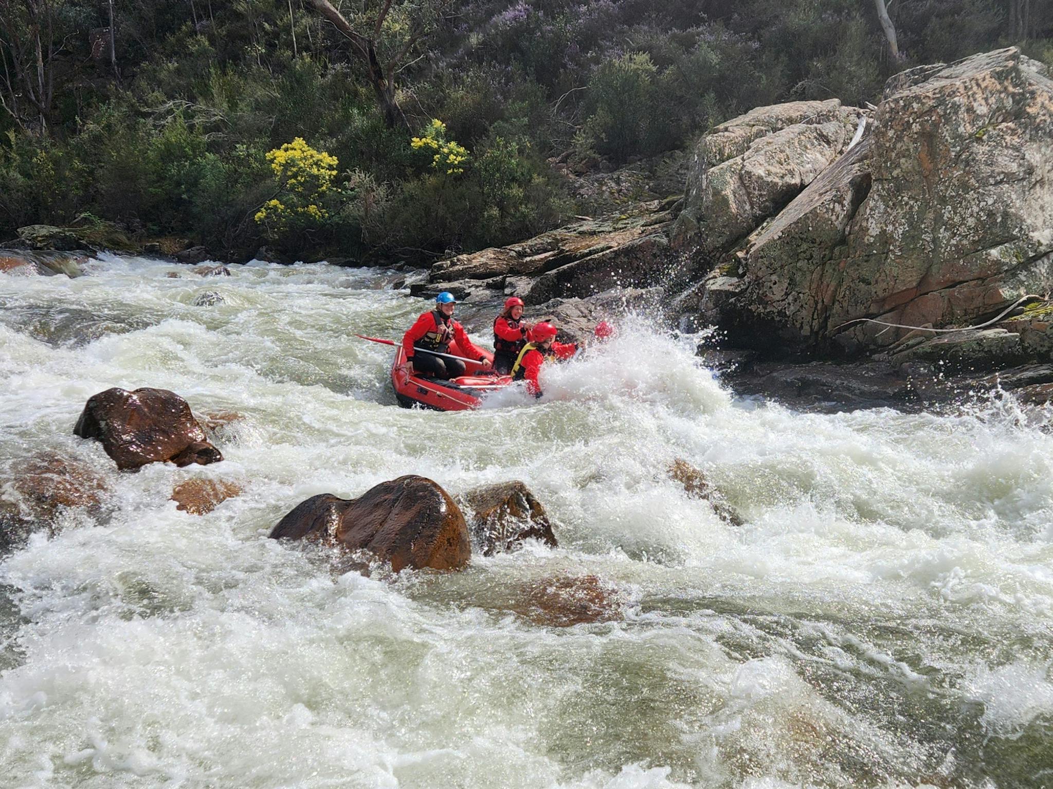 A female raft guide on the Mitta Mitta River with clients obscured by a splash.