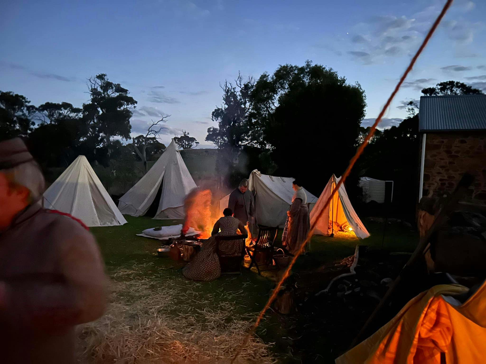 4 white bell tents surrounding a camp fire as evening fals at Glenbarr.