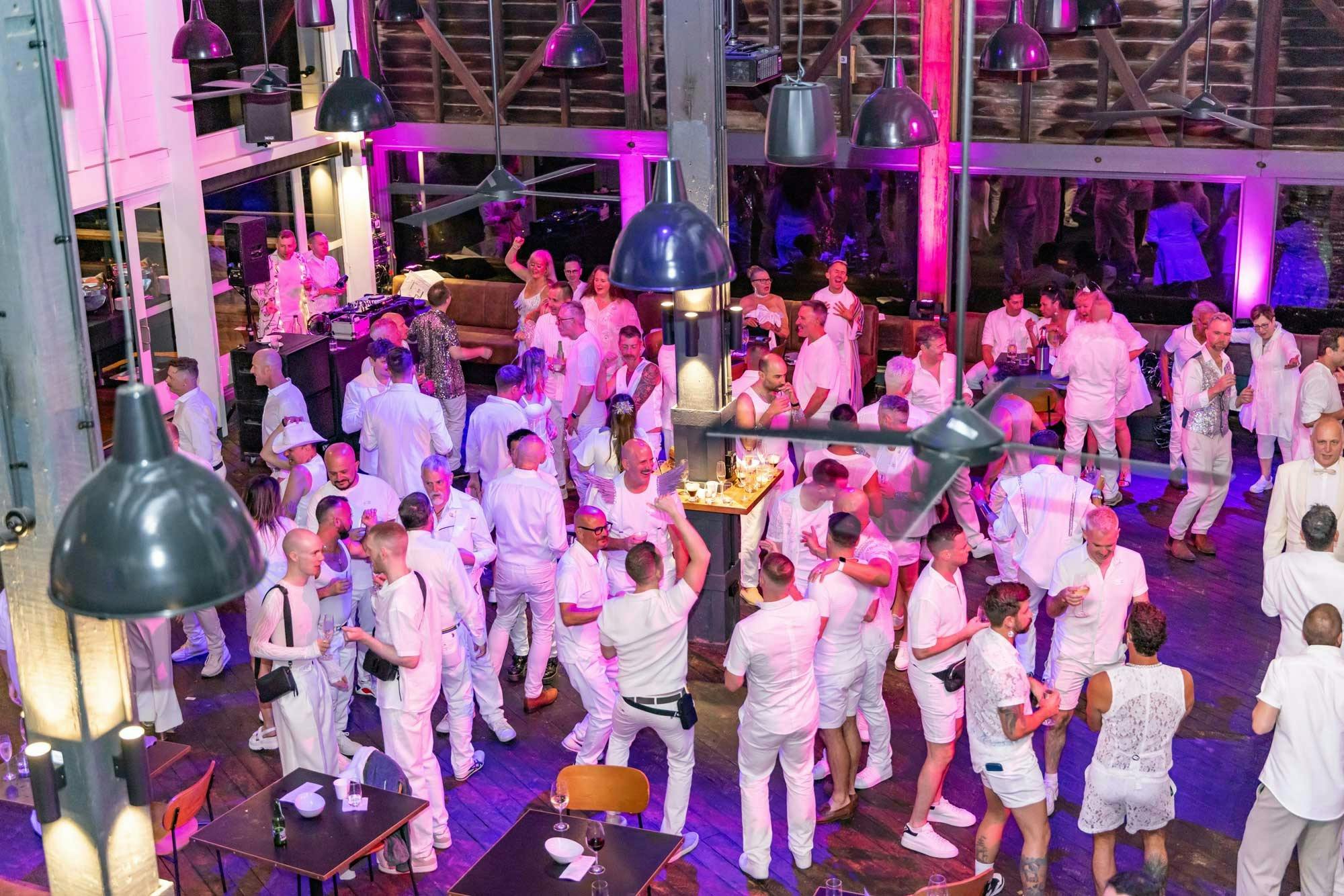 Guests in white socialising inside The Wharf Restaurant and Bar.