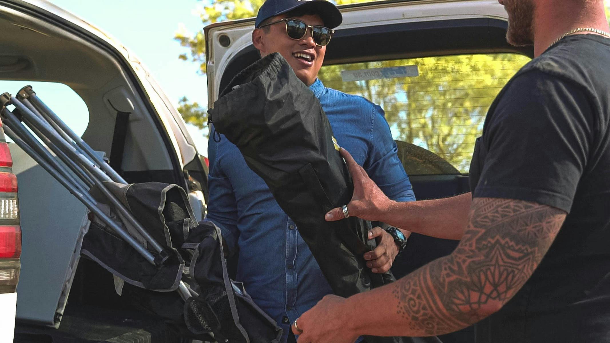 Two campers unpacking camping equipment from the back of a car