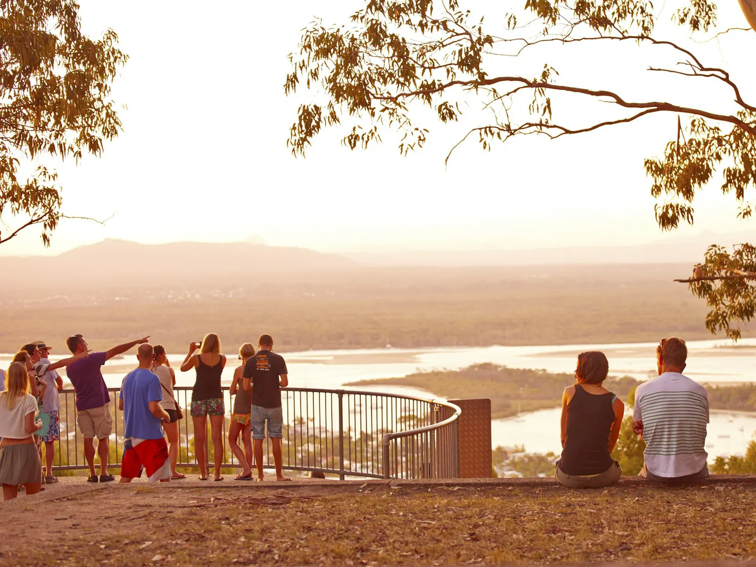 People standing and sitting at a lookout with views of Noosa  River and the township.