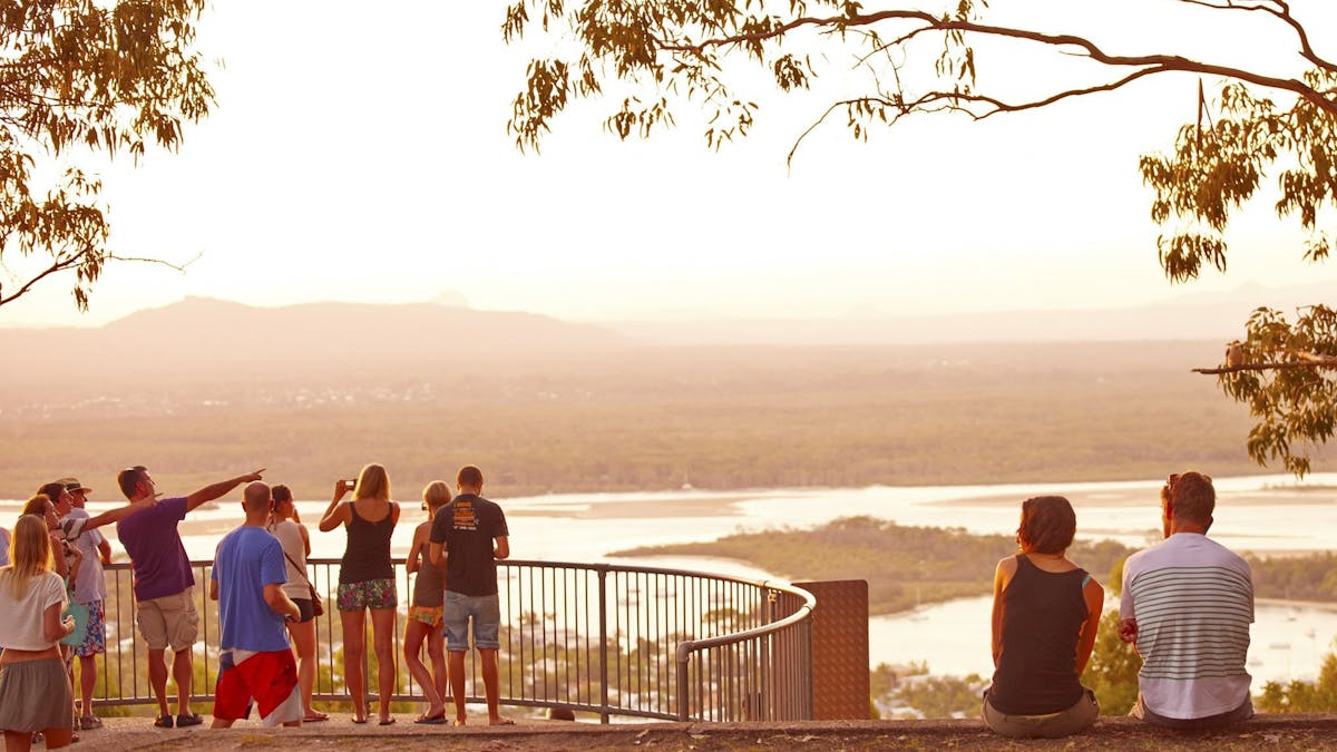 People standing and sitting at a lookout with views of Noosa  River and the township.