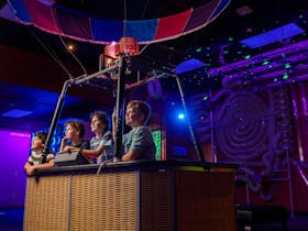Four children operating a hot air balloon exhibit