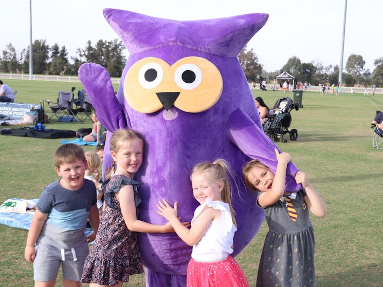 Children play with owl mascot