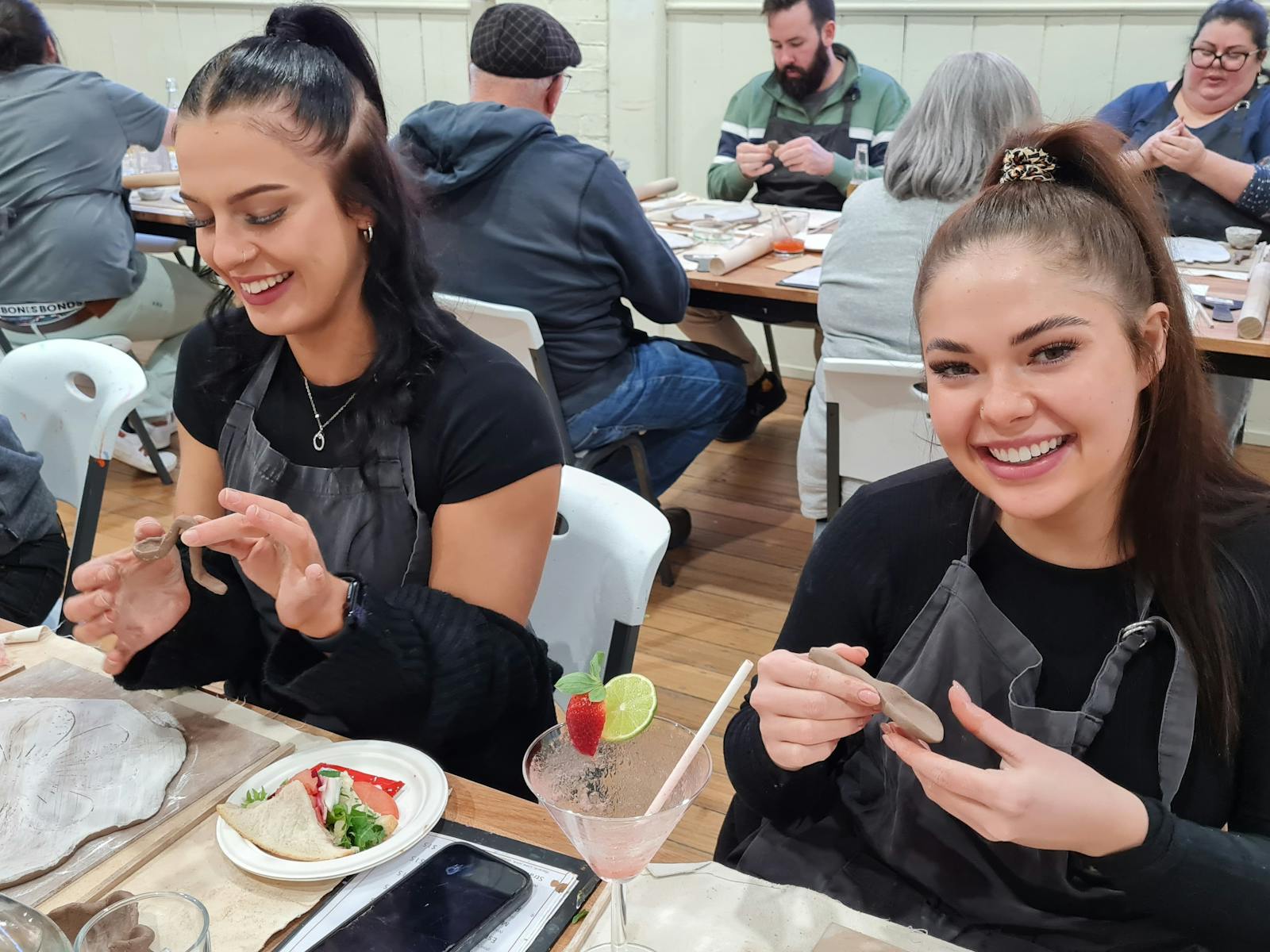 Two young woman crafting clay and drinking cocktails
