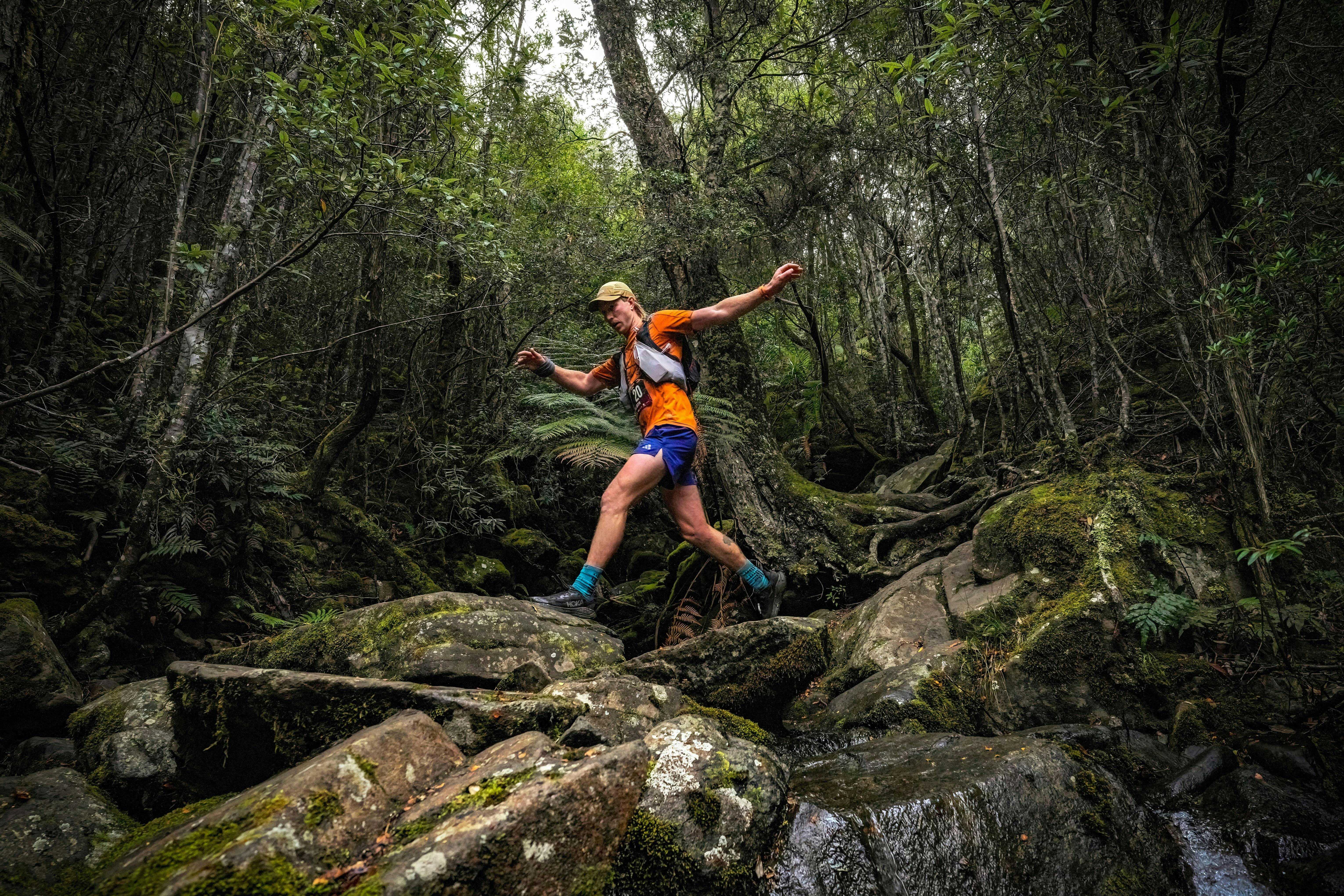 A male runner navigates rocks in the forest