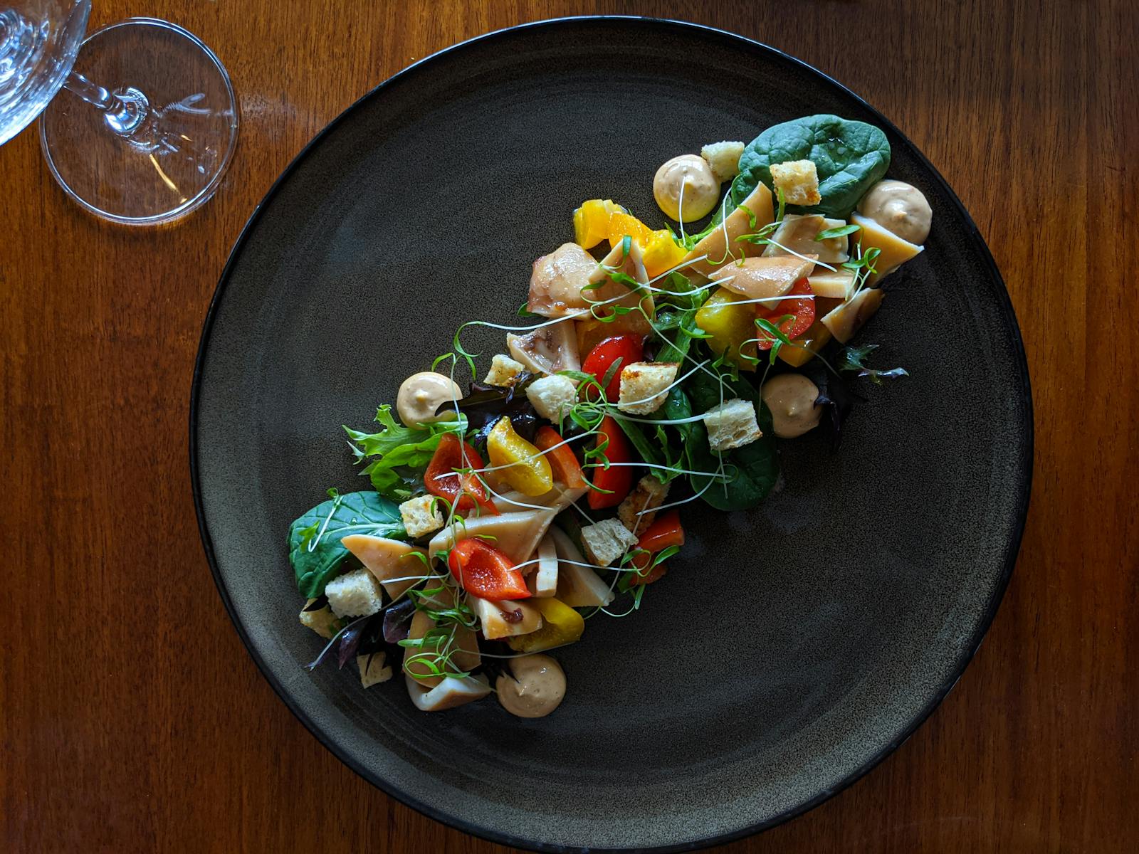 A salad presented horizontally on a round plate featuring Creole-style Tasmanian Octopus.