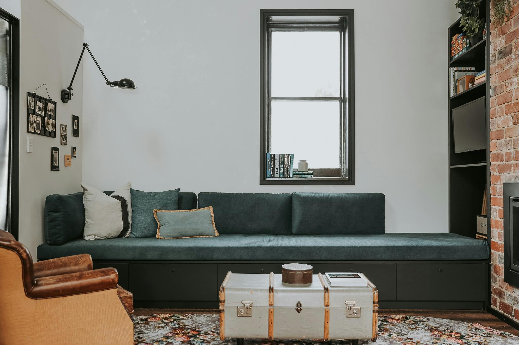 Large built-in couch under window with coffee table made from old trunk.