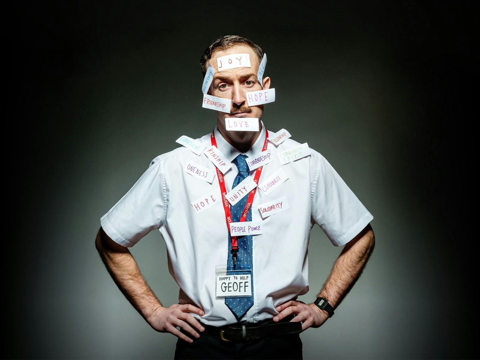 Man with tie standing with hands on hips with 'Geoff' nametag and words stuck to body