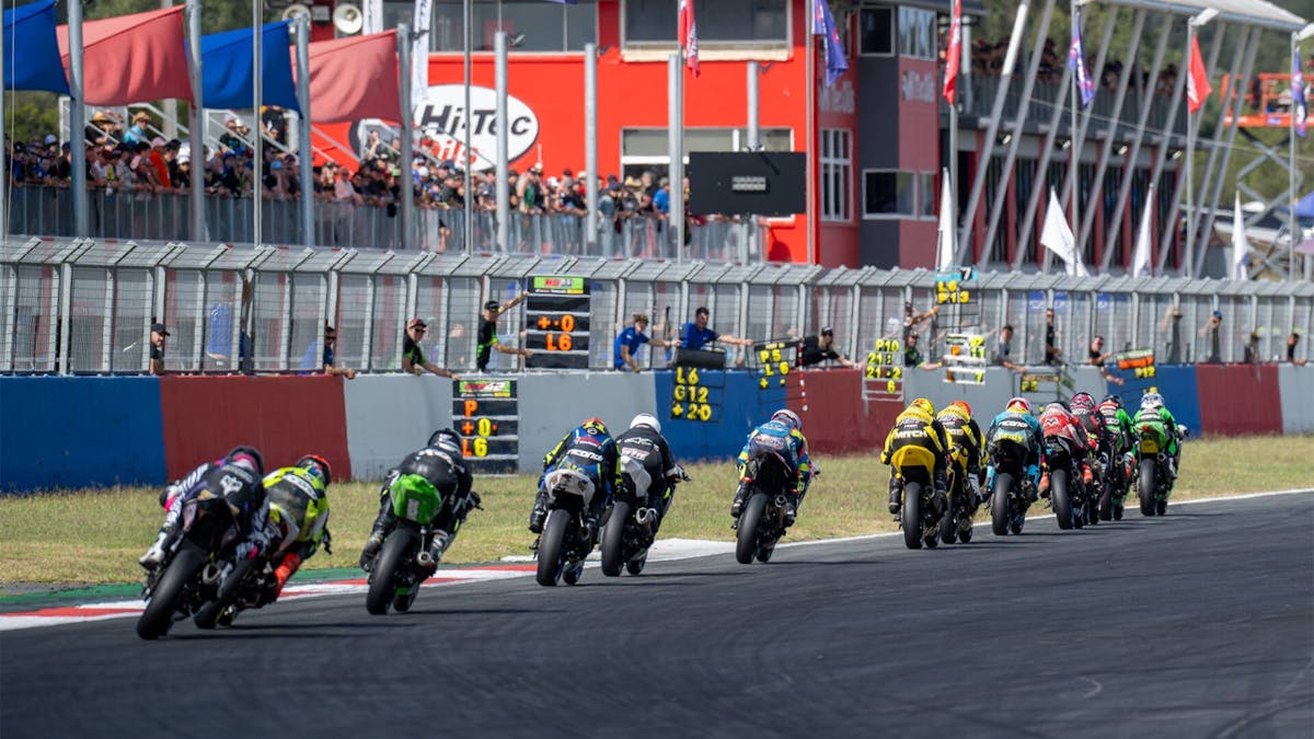 Bikes race down the main straight as a crowd cheers