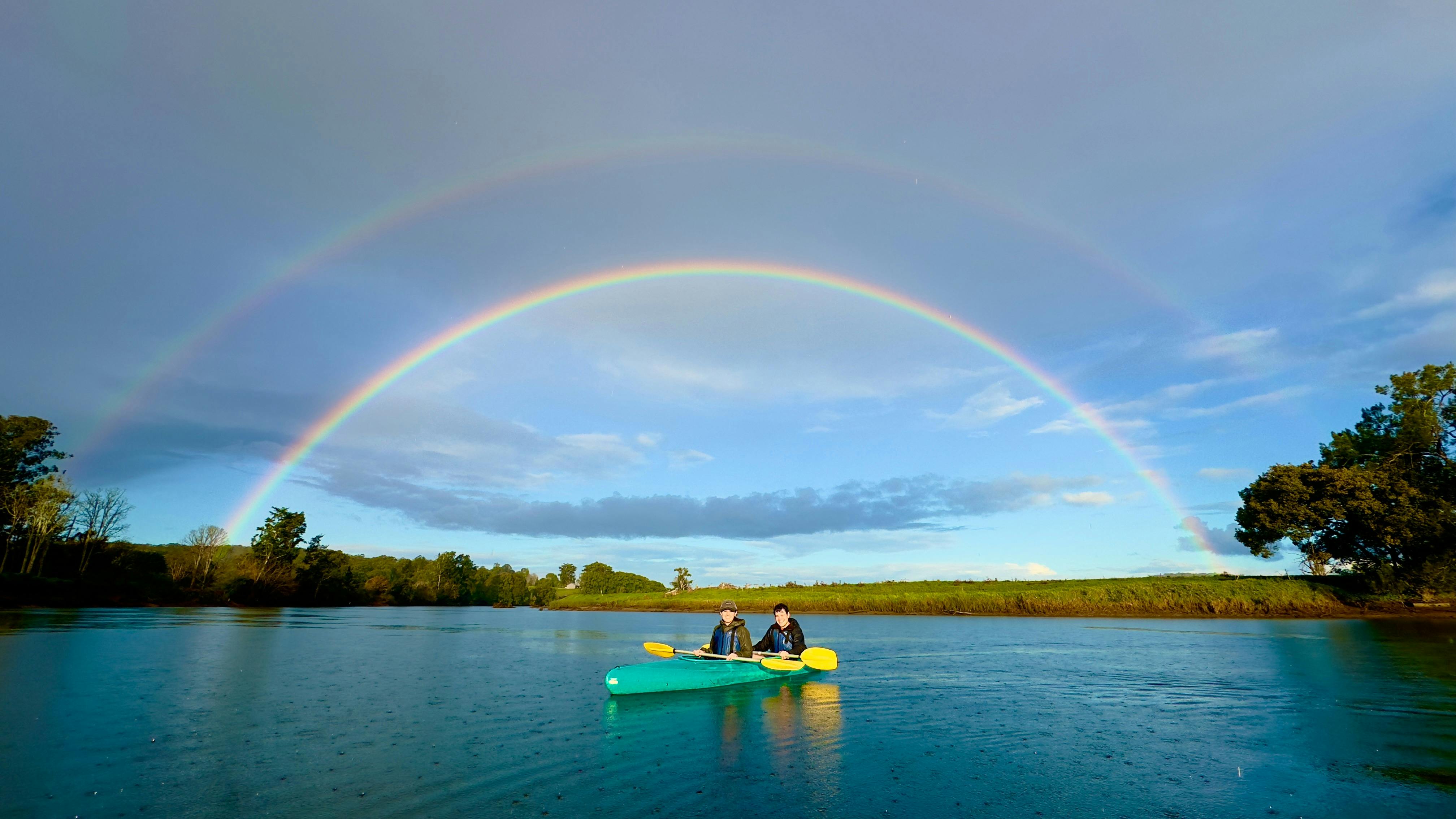 a couple in a double canoe with a Magnificent double rainbow with Bellingen Canoe Adventures