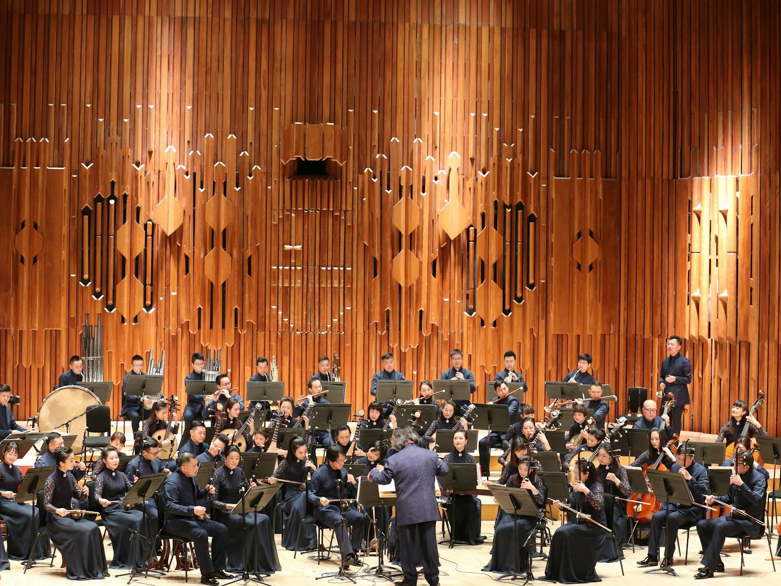Shanghai Chinese Orchestra performing on stage with traditional Chinese instruments, conducted under