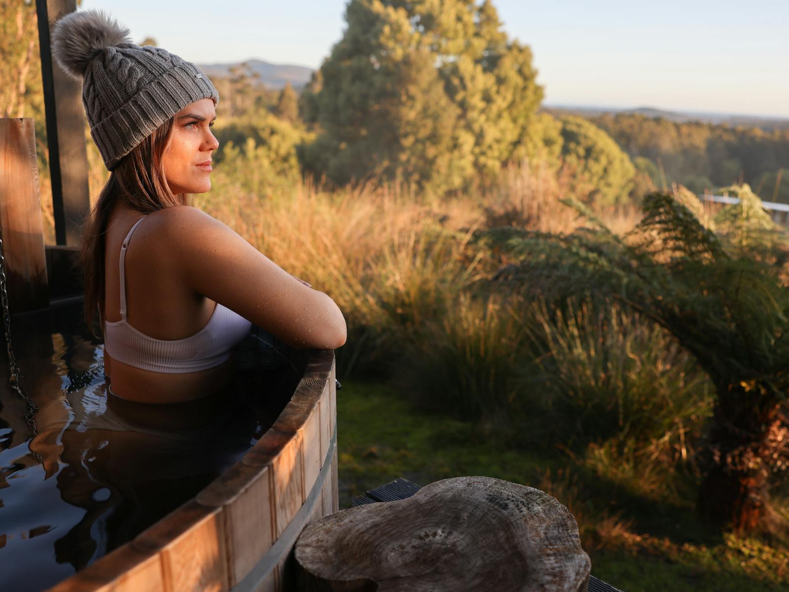 Lady relaxing in barrel hot tub facing out to Cloudy Bay