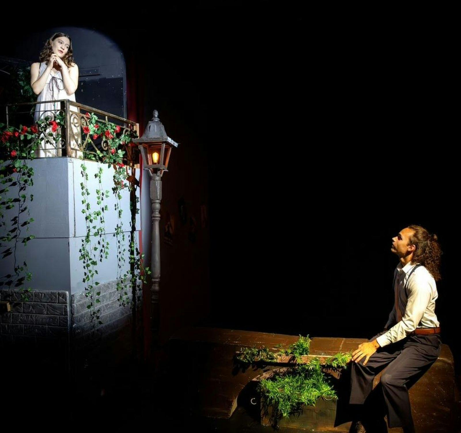 Roo Theatre - woman acting as Juliet up on a balcony with Romeo looking up to her.