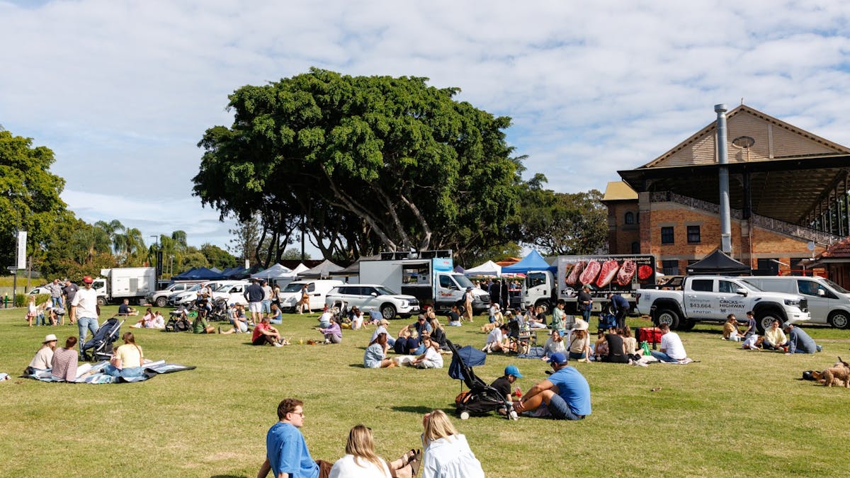 Market patrons happily enjoying the sunshine on the lawn at Jan Powers Farmers Markets Eagle Farm