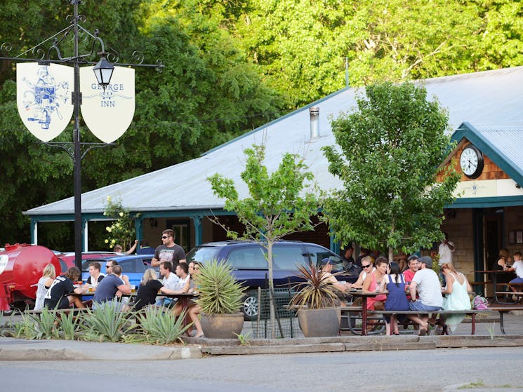 Front of establishment with people outside eating and enjoying a drink