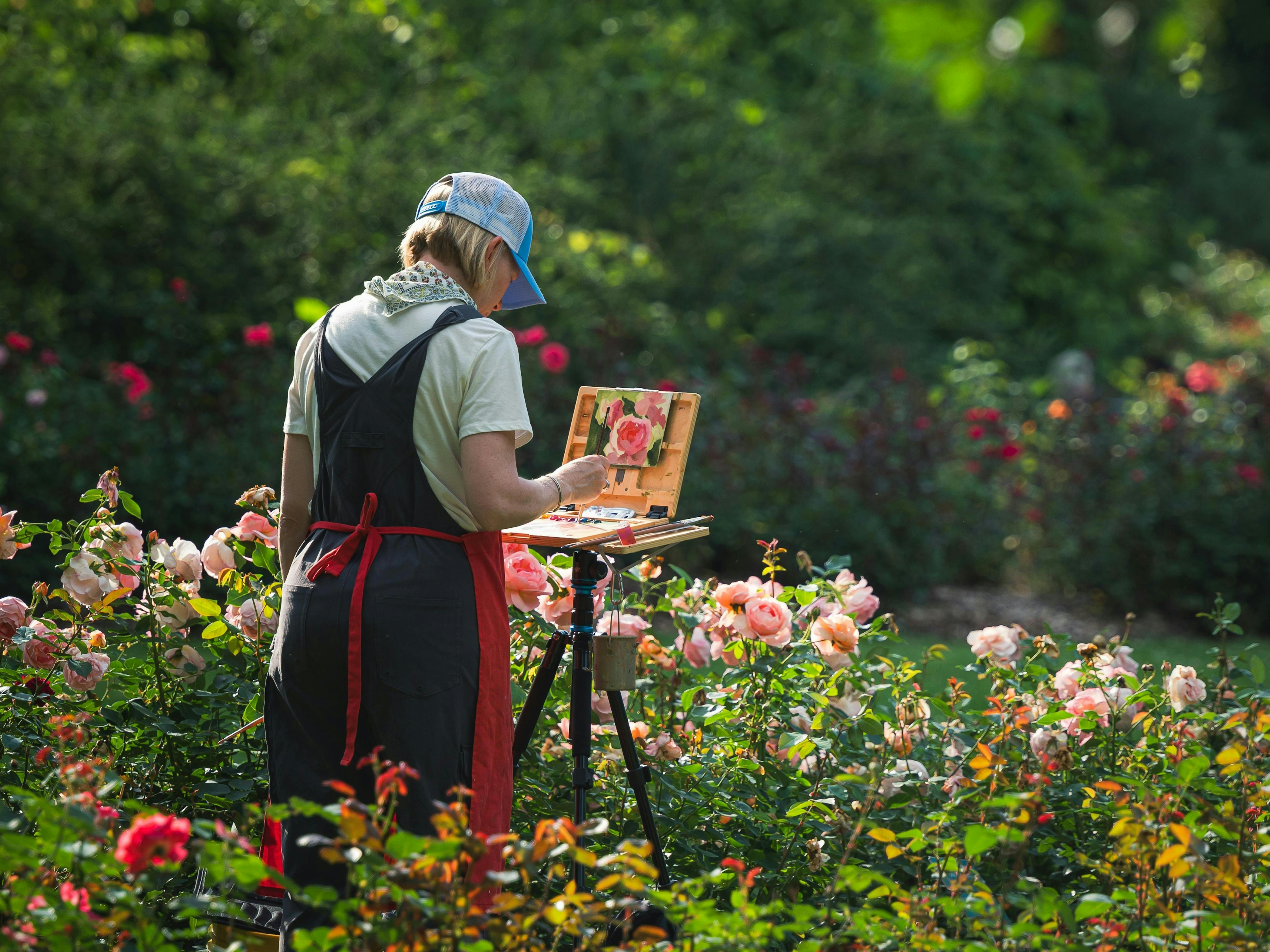 Artist painting in garden with small painting on easel