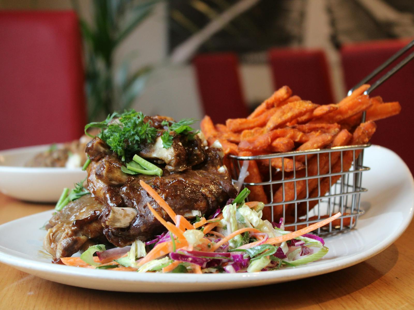 A delichious colourful meal with sweet potato fries in a wire basket, colourful salad and steak