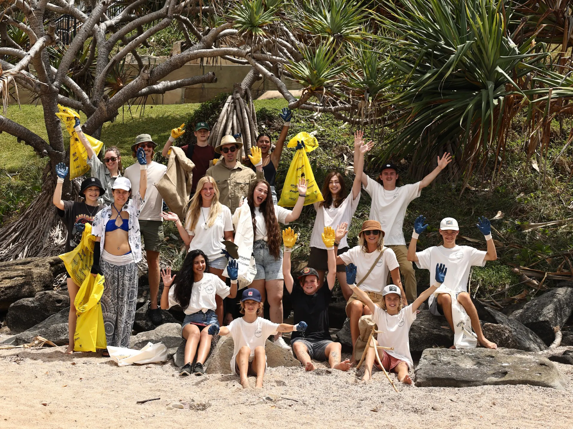 A group of people at the beach, with bags full of rubbish.