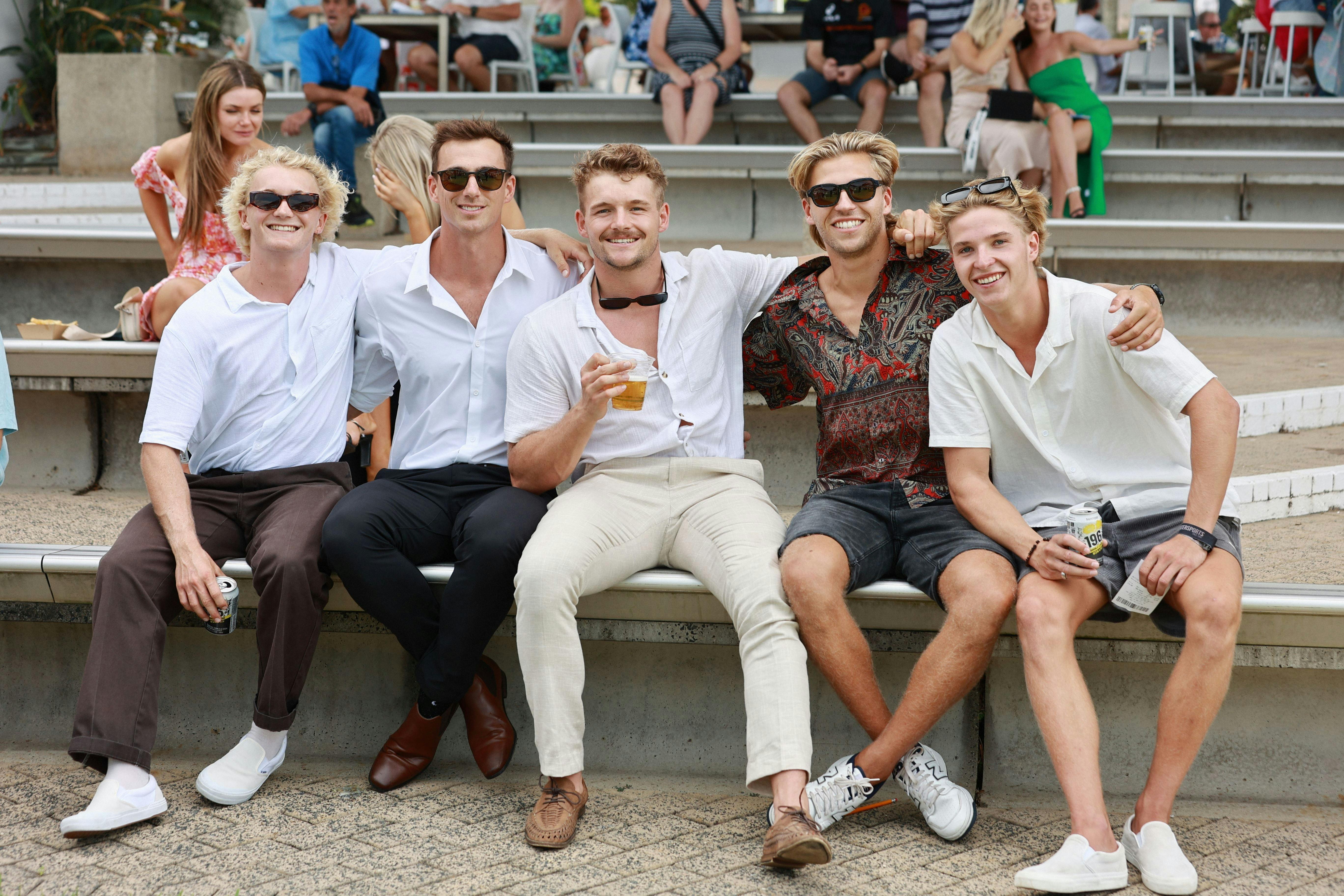 Young group of 5 boys sitting on a bench smiling